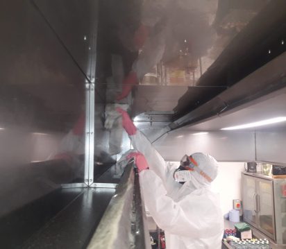Cleaning kitchen extract with PPE while on a ladder